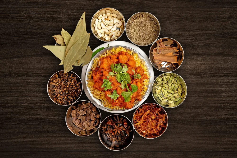 Biryani surrounded by whole spices on a dark wooden table